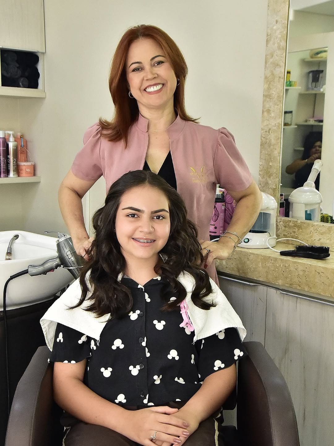 Nívia Carvalho ao lado de uma cliente com o cabelo finalizado